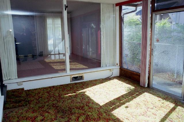 Totally enclosed "tv room", with green and orange carpet, curtains, many many plant hooks and nails, exterior sliding door